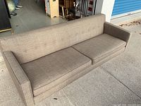 Full front view of beige sofa on pavement