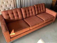 Full view of orange three-cushion sofa