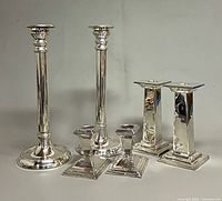 Group shot of all six silver-plated candlesticks showing height differences and base styles