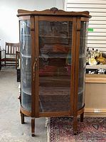 Front view of oak bow front curio cabinet showing glass door and curved side panels