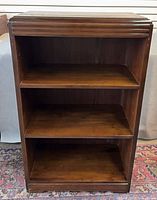 Front view of wooden bookcase showing three shelves and grooved top edge