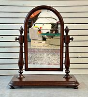 Front view showing arched mahogany mirror, turned supports, base, bun feet