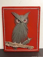 Front view of owl string art on red board