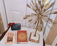 Sculpture standing on base beside two hardcover books