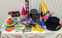 Wide shot of entire lot on table showing hats, horns, balloons, confetti, streamers and cannon