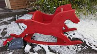 full side view of red wooden rocking horse on snow