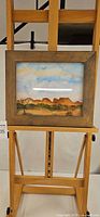 Full view of framed painting on easel
