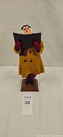 Front view showing entire Simpich caroler, gold coat, songbook, wood base