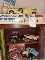 Overview of two wooden shelves showing model car kit boxes, built models, and tag