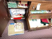 Open cabinet showing boxes of candles, candleholder, assorted linens and placemats