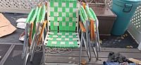 Five folded and one open green-webbed aluminum lawn chairs