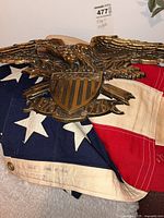 Folded U.S. flag and bronze-tone plastic eagle plaque together
