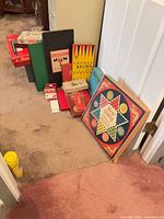 Group of boxed board games, card decks and card holders lined against wall