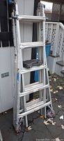 Folded aluminum Werner multi-position ladder with black tray resting on rung