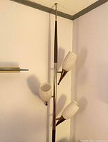 Full view of tension pole lamp with three ribbed glass shades