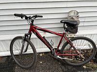 Full left-side view of red Schwinn mountain bike against siding