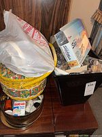 Overall view showing wicker sewing basket, plastic bin, thread spools, Bandaid case and StitchMate box