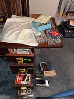 Cabinet drawers open showing bobbins, boxed attachments, thread spools and packages