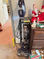Full view of Shark Rocket DuoClean stick vacuum standing with cord and base visible, box and manual nearby