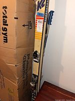 Full view of K2 skis with poles beside cardboard box