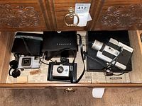 Drawer view showing Polaroid instant camera, Minolta Autopak 500, Canon Super 8 camera and their cases