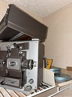 Projector on shelf with open cover and visible film reels