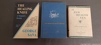 Three vintage medical books standing side by side showing covers
