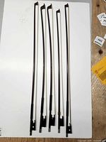 Five Glasser violin bows upright on white background