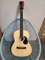 Full view of Monarch acoustic guitar front on chair