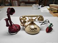 Front view of all three items showing Belle rotary phone centre, candlestick phone left, small iron right