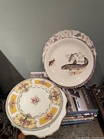 Front view of fish scene plate and floral cartouche plate