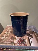 Front view of blue Le Creuset utensil holder on books