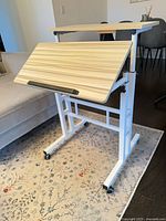 Front view showing full desk, tilting surface, frame and casters