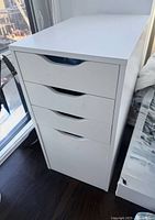Angled view of the white IKEA Alex drawer unit beside window