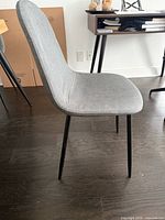 Side view of grey upholstered chair showing seat, backrest and black legs