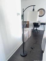 Full view of black arc floor lamp with white shade