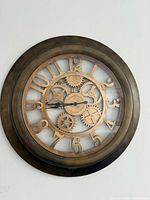 Front view of round brushed gold skeleton wall clock