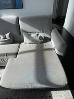 Full view of sofa showing three seats, chaise on right, two pillows, flip-up headrests