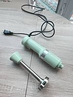 Blender motor body and detached blending arm displayed on tabletop