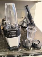 Full blender assembled with extra cup and lids visible