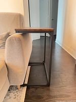 Side view of C-shaped table showing black metal frame under sofa arm