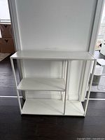 Front view of white metal console table with two shelves