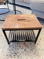 Front angle view showing wood top with slot and metal frame with slatted shelf