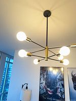 Chandelier illuminated, showing black arms, gold accents and ceiling canopy