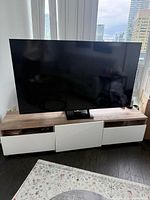 Front view of IKEA TV unit with TV on top showing three white fronts