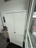 Front view of closed white two-door IKEA wardrobe