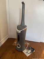 Full view of gray Air Innovations humidifier with nozzle and power cord on wood floor