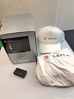 Group view of Leica Q3 box, hat, T-shirt, battery