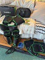 Entire kit laid out: leg sleeves, foot pads, controller, power cable, manual, carry bag, box, gel packs