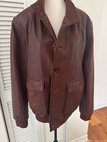 Front view of perforated brown leather Danier jacket on mannequin